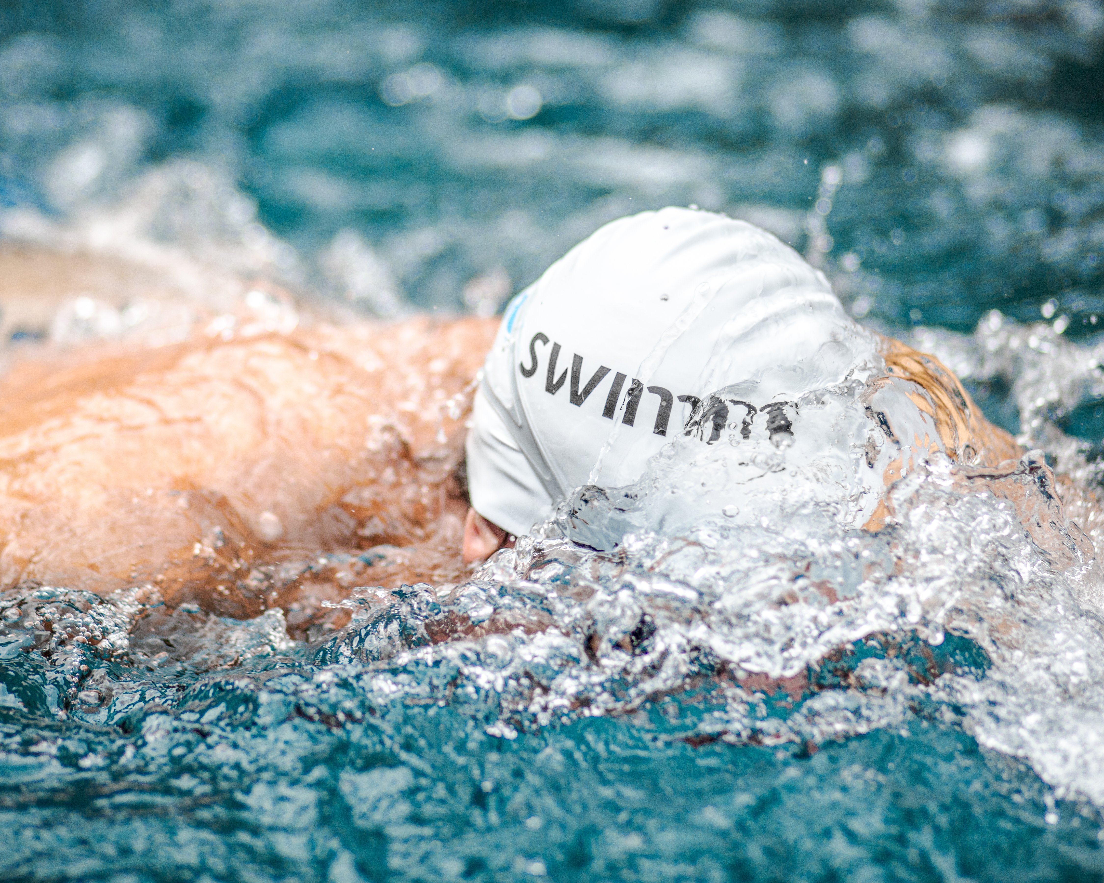 Een zwemmer met een badmuts met het SWIMM-logo tijdens IRONMAN