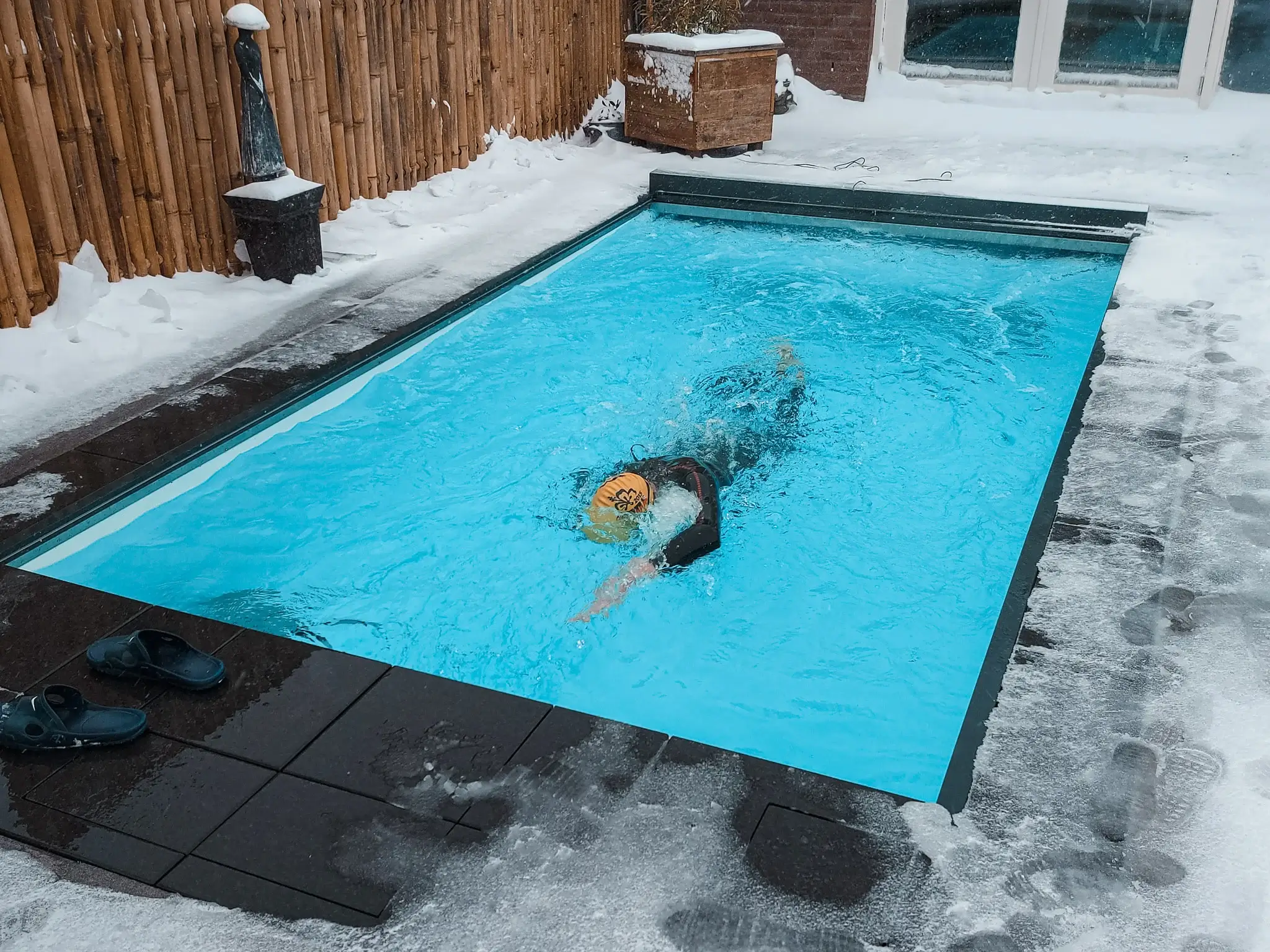 Koud water zwemmen - man zwemt in Swimm met sneeuw rondom het bad